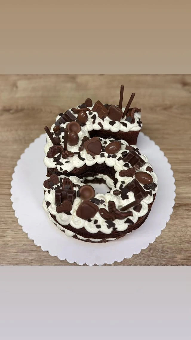 Schokoladen-Geburtstagstorte mit weißen Cremerosetten und Schoko-Sticks