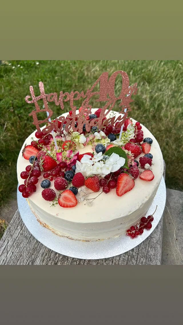 Zweistöckige Geburtstagstorte in Weiß mit frischen Erdbeeren und Himbeeren