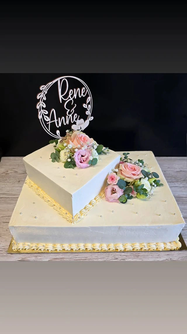 Zweistöckige Hochzeitstorte in Creme und Gold mit Rosenkranz und Schriftzug René und Anne