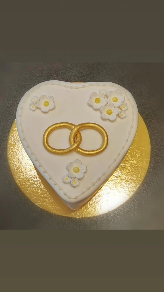 Hochzeitstorte in Herzform mit Goldring und Margeriten