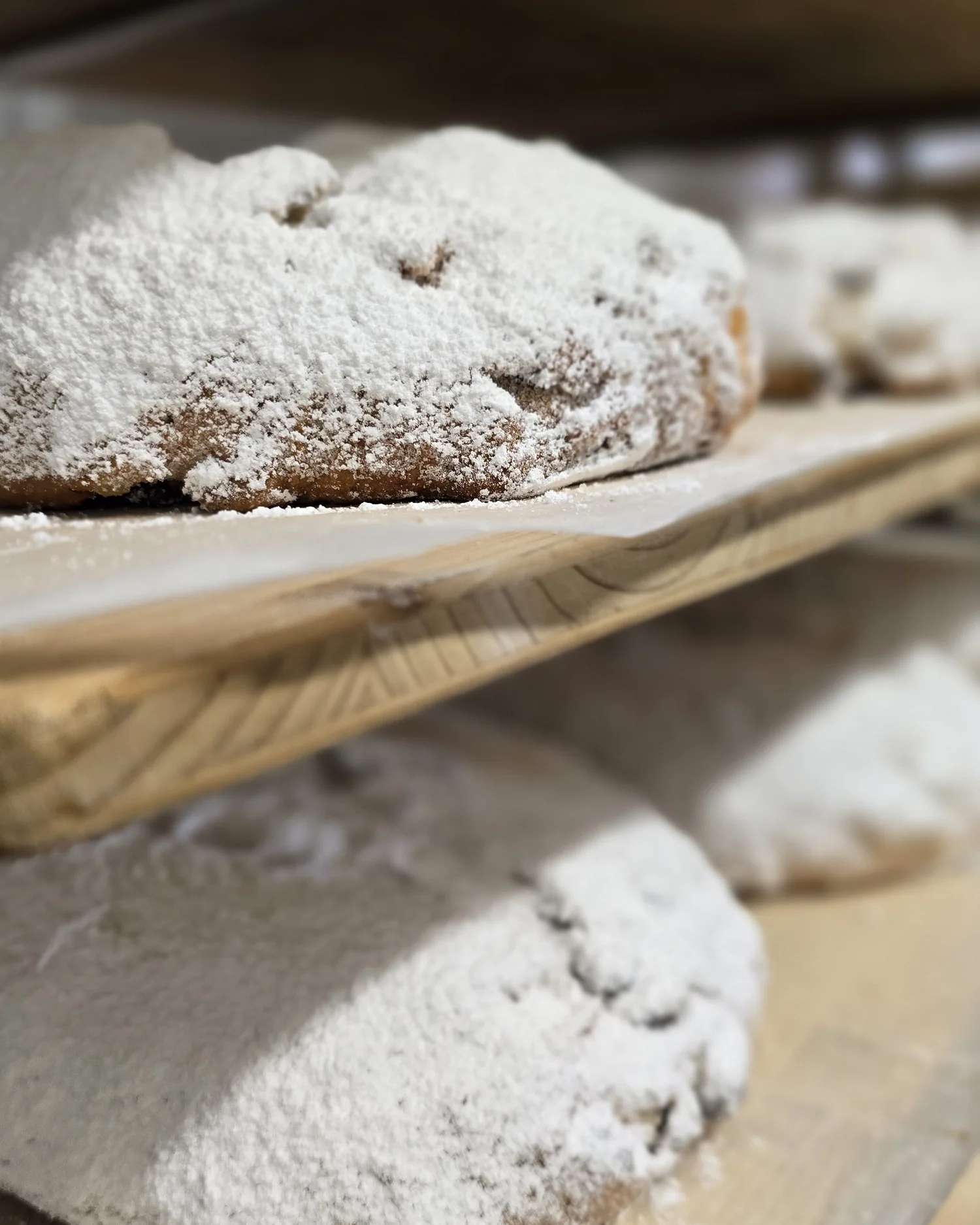 Gezuckerte Dresdner Christstollen auf Holzregalen in der Backstube der Landbäckerei Friedrich
